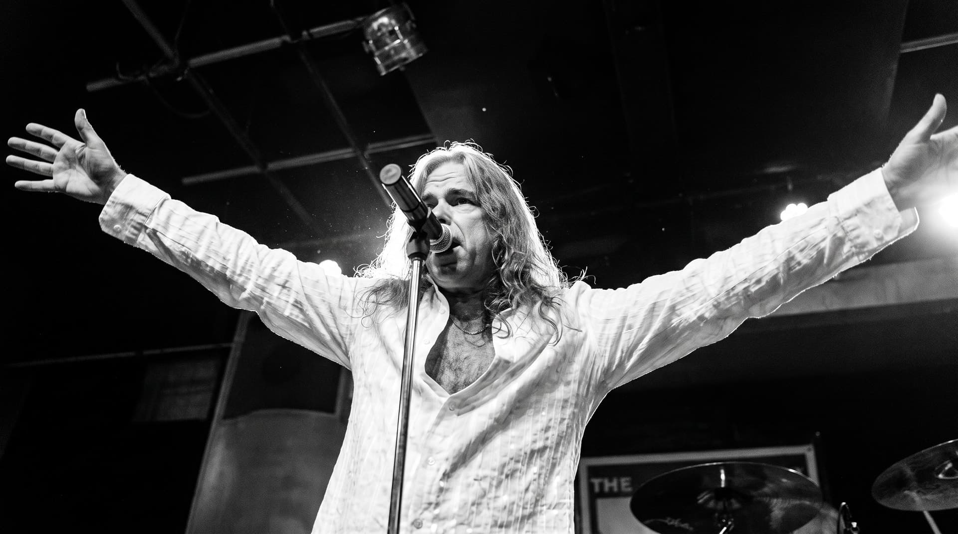 Brian Bee Frank on stage with arms outstretched at the microphone